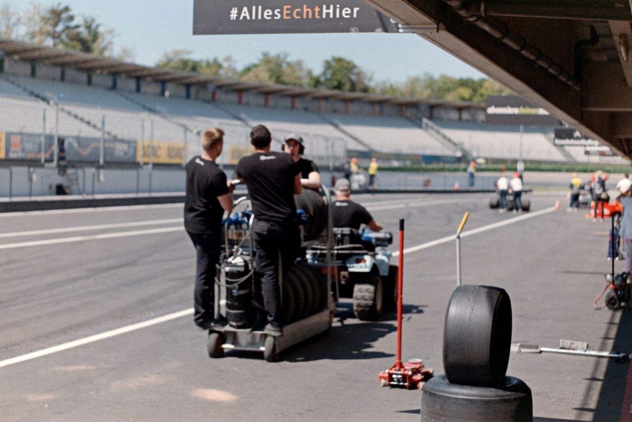 services-03 Pit crew preparing equipment on a motorsport track under bright daylight.